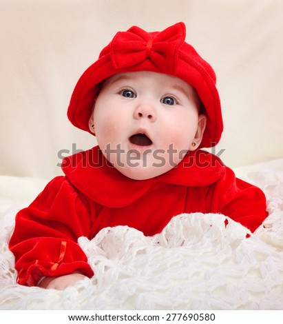 portrait of a cute little baby girl dressed in red with a surprised face expression