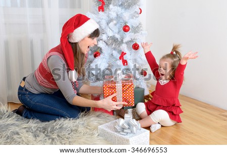 happy family mother and little daughter in front of christmas tree with presents and gifts for holidays