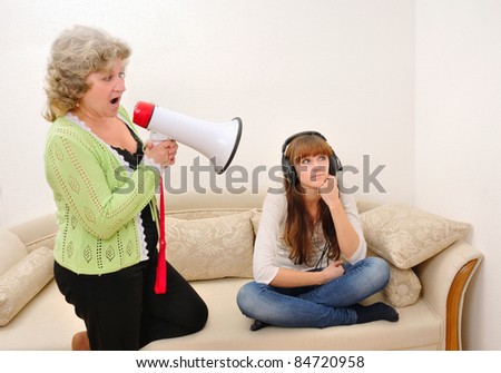 mother shouting at her daughter with a megaphone while she indifferently listens to music