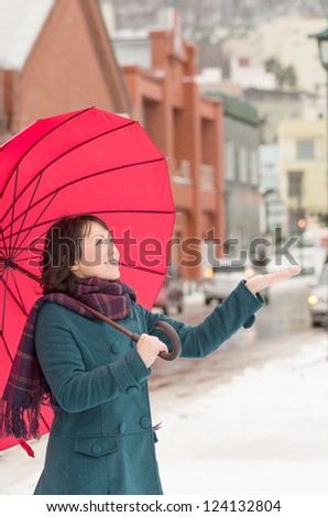 Young Asian woman holding up her umbrella in winter city