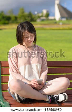 Young Asian woman listening to music with smart phone in a park.