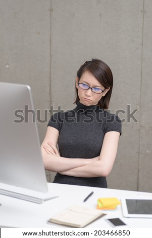 Young Asian woman thinking to watch a desktop computer.