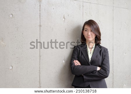young business woman leaning on concrete wall.