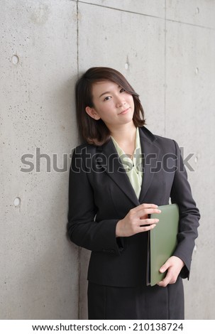 young business woman leaning on concrete wall.