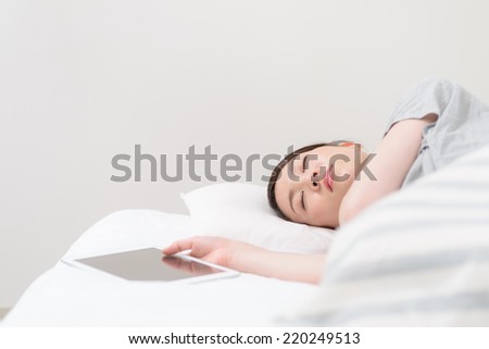 Young Asian woman sleeping with having a tablet PC