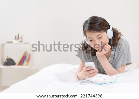 Young Asian woman listening to music with smart phone.
