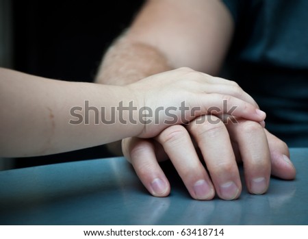 Child\'s hand on top of adult\'s hand