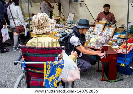 TAKAYAMA, JAPAN - OCTOBER 21: An Japanese artist visiting stands plays music to promote his new album in the Jinya-mae morning Market on October 21, 2011 in Takayama, Japan.