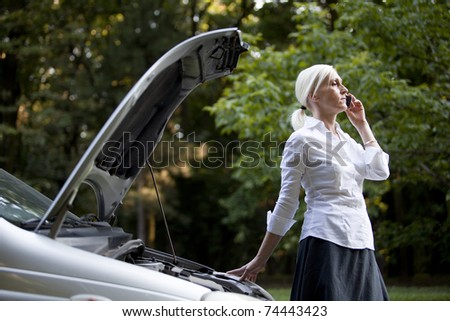 Woman besides her broken car talking on the cell phone