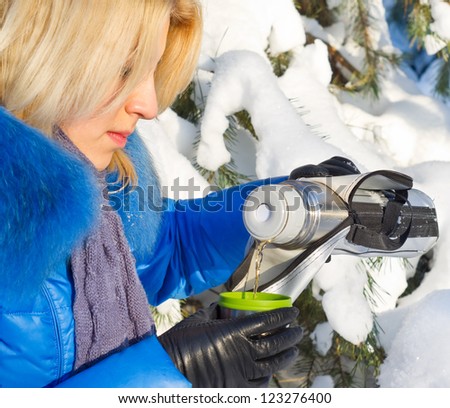 beautiful girl with thermos and cup hot tea in frosty winter day