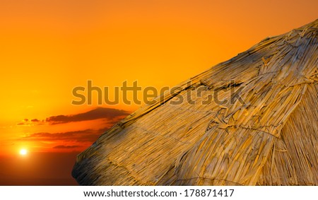 Thatched roof of wood house on the sea shore at sunset