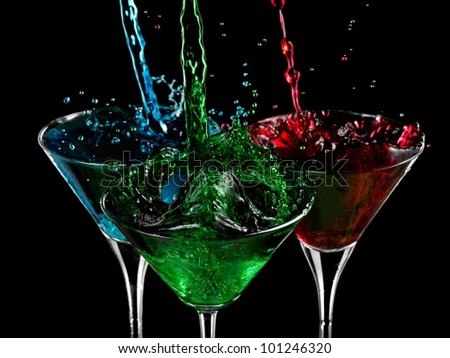 Red, green and blue cocktails splash in martini glasses