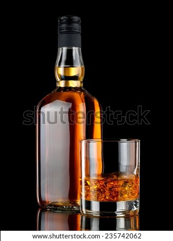 Glass with whiskey and a full whiskey bottle