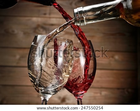 White and red wine pouring on wood background
