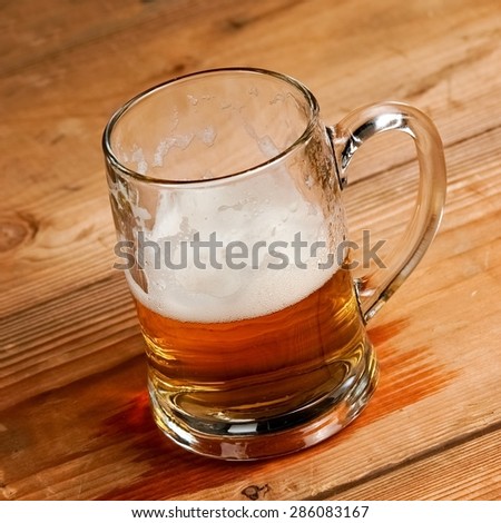 Half full beer mug on wood