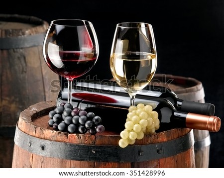 Red and white wine and grapes over a old wine barrel
