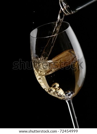 White wine pour in a glass on black background