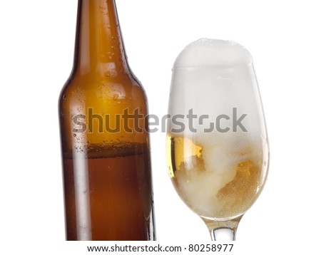 Glass with beer and foam and a brown bottle