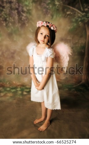 Beautiful young girl wearing angel wings and flower halo with somber expression