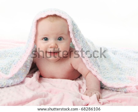 Cute baby girl lying on her tummy over a pink blanket, with a hand crocheted blanket over her head