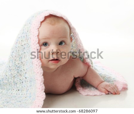 Cute baby girl lying on her tummy with a hand crocheted blanket over her head