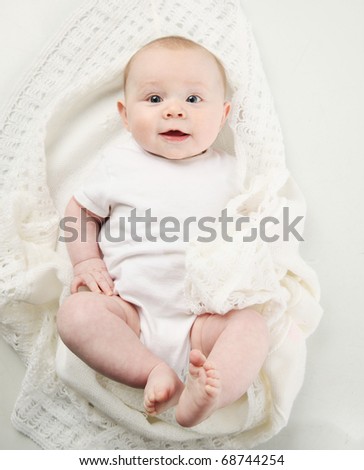 bright closeup portrait of adorable baby lying on a white handmade blanket