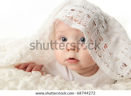 bright closeup portrait of an adorable baby with a white knit blanket draped over head