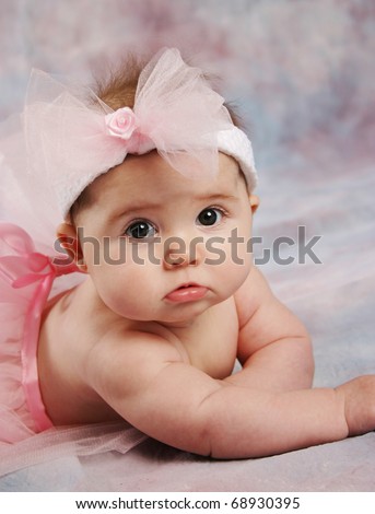 Portrait of a beautiful baby girl wearing a pink ballet tutu and pink hair bow headband