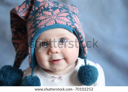 Portrait of an adorable baby girl with big blue eyes wearing a knit pink and blue winter hat