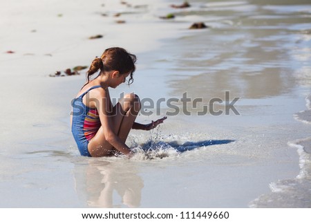 young girl claps her hand in the water