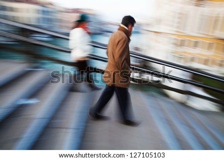 people in motion blur on the move on a bridge in Venice