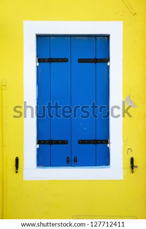 blue window shutters on a yellow colored house of Burano