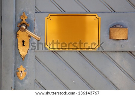 detail of an old door with a door handle and a brass plate