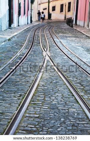 tracks of cable cars in Lisbon, Portugal, with walking people in the background