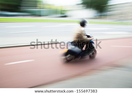 scooter rider on a city street in motion blur
