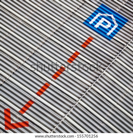 parking sign and an arrow at a corrugated sheet metal facade