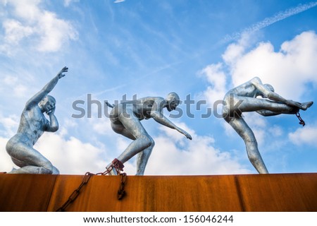 ROTTERDAM, NETHERLANDS - SEPTEMBER 21: modern sculpture on September 21, 2013 in Rotterdam-Delfshaven. The sculpture of three figures is in front of the modern nautical college STC.