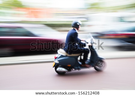 Scooter Rider On A Bike Lane In The Busy City Traffic In Motion Blur