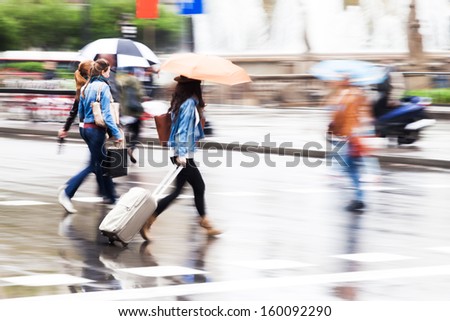 shopping and traveling women with umbrellas crossing the street on a rainy day