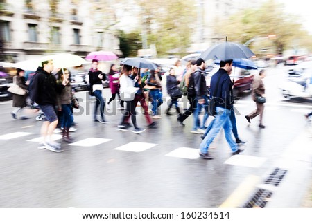 crowds of people crossing the street on a rainy day in the city