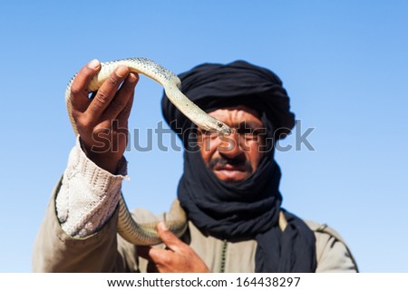 AIT-BEN HADDOU, MOROCCO - NOVEMBER 20: unidentified Tuareg man with turban holding snake in the hand on November 20, 2013 in Ait-Ben Haddou. The Tuareg are nomadic people of the Berber.