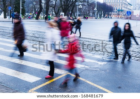 people in motion blur crossing the zebra crossing on a hazy day in winter
