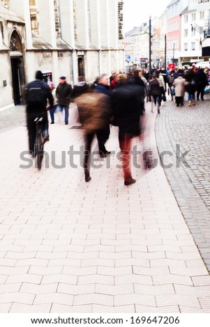 crowd of people in motion blur walking the shopping street of a city