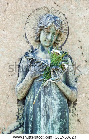 MILAN, ITALY - FEBRUARY 22: woman sculpture with a flower on the Cimitero Monumentale on February 22, 2014 in Milan. The central cemetery is well-known for its artistic and famous graves.