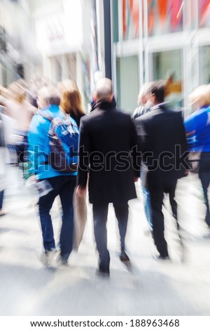 crowd of walking people in the busy shopping street of the city with creative zoom effect