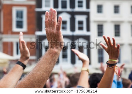 crowd of people show their approval by raising their hands