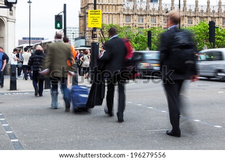 people crowd in motion blur crossing a street near Big Ben in London