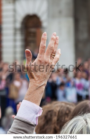 older woman raising her hand in the crowd