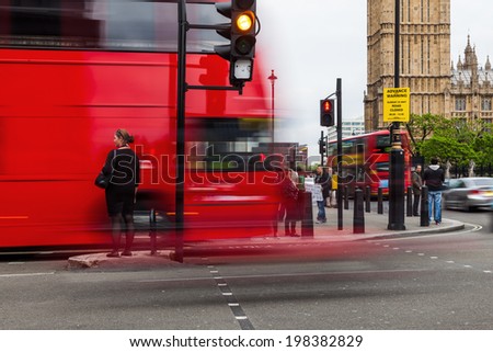 LONDON - MAY 21: unidentified people at a junction near Big Ben with a blurred red bus on May 21, 2014 in London. London is one of the most important cultural, financial and trade centres in the world