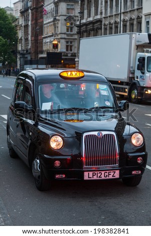 LONDON - MAY 21: London Taxi with unidentified people on May 21, 2014 in London. The traditional London Taxi is one of the world reknown iconic symbols of London.
